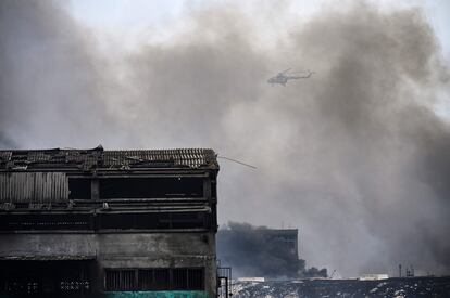Un helicóptero de extinción de incendios sobrevuela el depósito de combustible que estuvo envuelto en llamas durante cinco días después de que un rayo cayera sobre uno de sus tanques, el 10 de agosto de 2022.