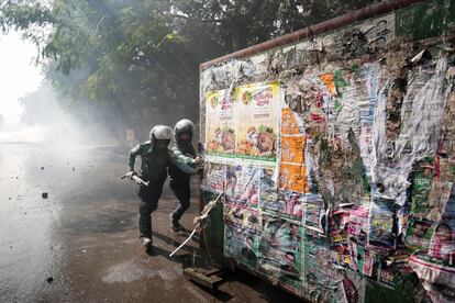 Dos agentes de policía empujan una barricada para detener a los manifestantes que exigen la cancelación de un plan de construcción de una central eléctrica de carbón en Bangladesh. La infraestructura se ubicará cerca de los bosques de manglares en la costa de Daca.