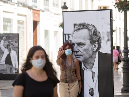 Una mujer posa junto a un cartel de José Coronado en la exposición 'Cine de cerca' en la calle Marqués de Larios, en Málaga.