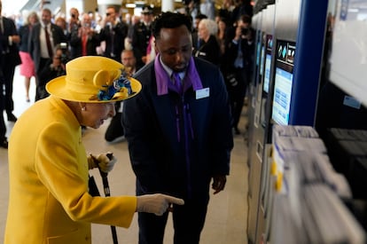 Isabel II, utilizando una de las máquinas expendedoras de billetes de metro, en la estación de Paddington, en Londres, este martes.