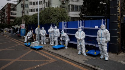 Pandemic-prevention workers in protective suits stand outside a residential compound under lockdown in Beijing. 