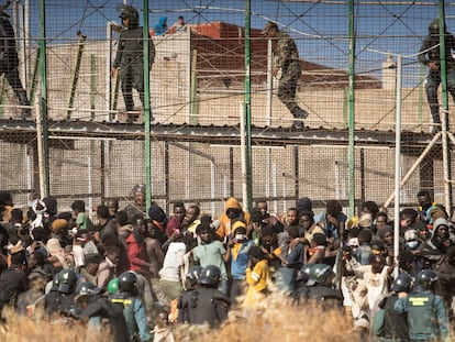 Inmigrantes y policías en la valla de Melilla, el 24 de junio.