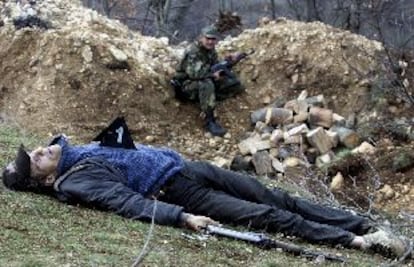 Un guerrillero albanés muerto ayer cerca de Presevo. Al fondo, un policía serbio.