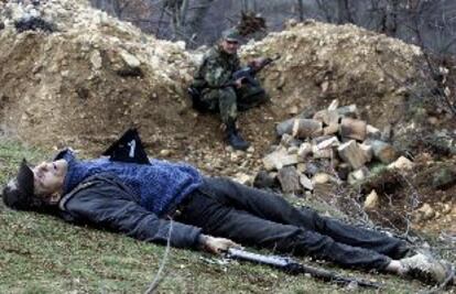 Un guerrillero albanés muerto ayer cerca de Presevo. Al fondo, un policía serbio.
