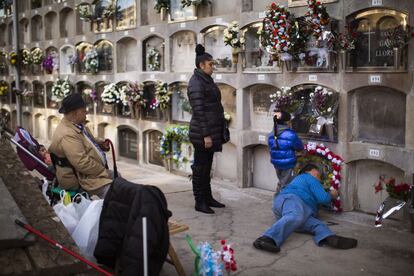 Una familia decora con flores la tumba de un familiar en un cementerio de Barcelona.