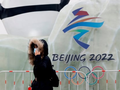 Una mujer pasea ante un emblema de Pekín 2022.