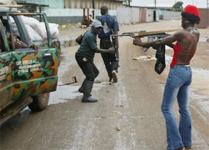 Una guerrillera apunta con un Kaláshnikov a un grupo de saqueadores ayer en el puerto de Monrovia.

 / ASSOCIATED PRESS