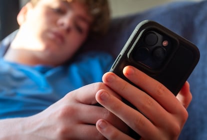 Un niño de 14 años mira la pantalla de un móvil.