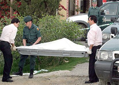 En la imagen, la policía y operarios retiran el cadáver de uno de los hombres encontrados en la carretera.