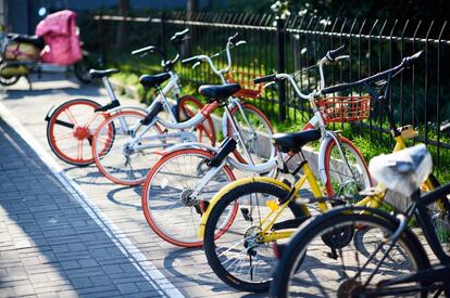 Una bici Ofo (amarilla) y varias Mobike esperan ser usadas por alguien en una calle de Shanghái.