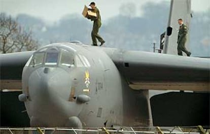 Dos militares encargados del mantenimiento de un bombardero B-52 estadounidense pasan sobre el avión.