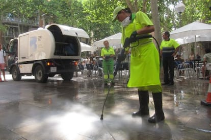 Operarios limpian el suelo en una calle de Barcelona.