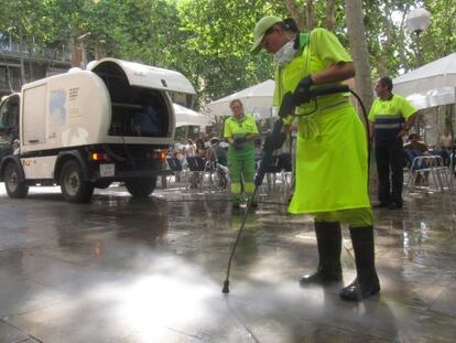 Operarios limpian el suelo en una calle de Barcelona.
