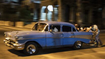 Varios jóvenes empujan uno de los viejos coches que recorren La Habana para arrancarlo de nuevo.