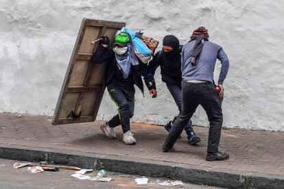 Los manifestantes se protegen con un escudo improvisado durante los enfrentamientos con la policía antidisturbios en Quito (Ecuador). 