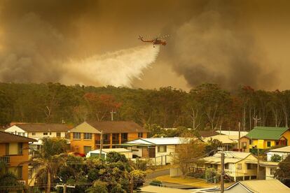 Un helicóptero descarga agua este viernes sobre los incendios que arrasan los bosques de la ciudad de Harrington (Australia).