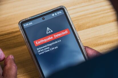Un hombre recibe una alerta de sismo a su teléfono móvil.