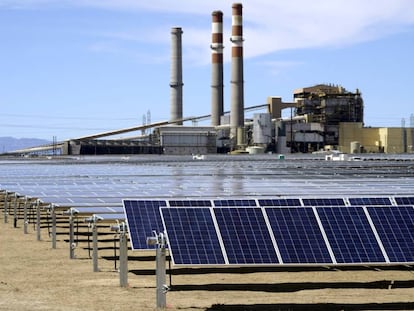 Paneles solares en Pueblo, Colorado. Al fondo, una planta de carbón de Xcel Energy.