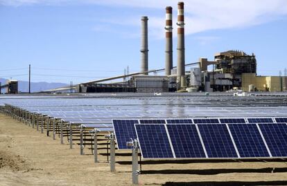 Paneles solares en Pueblo, Colorado. Al fondo, una planta de carbón de Xcel Energy.