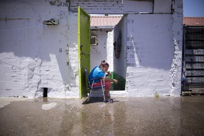 María se refresca con una manguera en el exterior de su chabola, en el asentamiento chabolista de El Vacie en Sevilla.