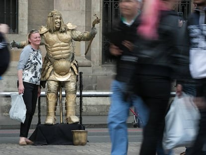 Una turista es fa una foto amb una estàtua de la Rambla.