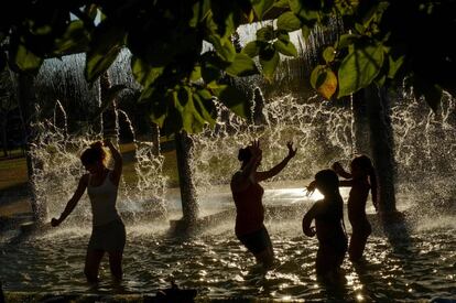 Personas se refrescan en una fuente durante un día caluroso de verano, en Pamplona.