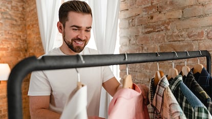 Un hombre mirando sonriente el interior de una camisa emperchada