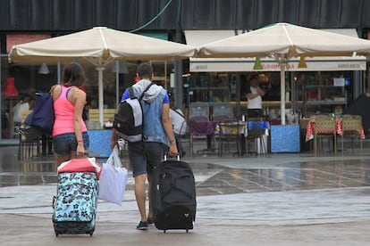 Unos turistas caminan con sus maletas por el barrio de La Barceloneta. EFE/Archivo