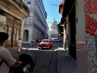 Un vehículo clásico en una calle con murales de la bandera cubana, junto al Capitolio, en La Habana.