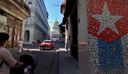 Un vehículo clásico en una calle con murales de la bandera cubana, junto al Capitolio, en La Habana.