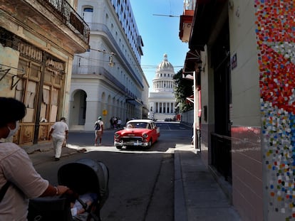 Un vehículo clásico en una calle con murales de la bandera cubana, junto al Capitolio, en La Habana.