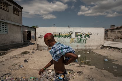 A young man walks past a mural with the name of an armed gang from the Boston neighborhood of Cité Soleil.