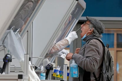 Un médico recoge una muestra de hisopo de un viajero en una cabina del centro de pruebas rápidas de coronavirus, en el aeropuerto israelí Ben-Gurion de Lod, cerca de Tel Aviv. Las autoridades de Israel han anunciado la ampliación del confinamiento hasta el 31 de enero, después de que el país confirmara más de 10.000 casos diarios de coronavirus por primera vez desde el inicio de la pandemia.