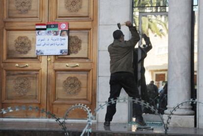 Un manifestante golpea con un martillo una ventana de la Embajada de Libia en la capital de Túnez.