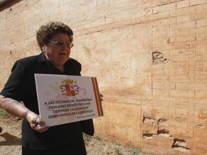 Una mujer, familiar de un fusilado en la tapia del cementerio de Granada, coloca una placa en el lugar en el que fue asesinado.