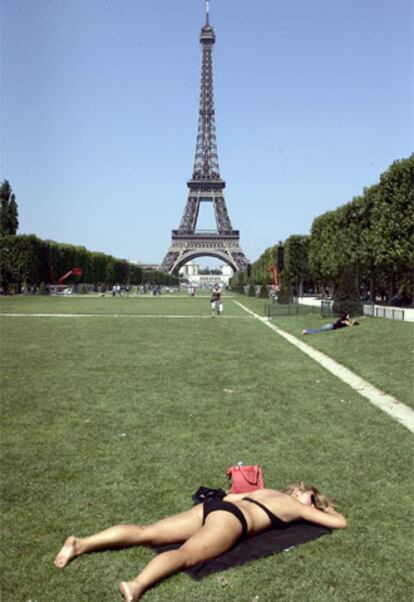 El buen tiempo ha acompañado la festividad nacional francesa. En la imagen, ajena a los desfiles, una mujer toma el sol cerca de la Torre Eiffel.