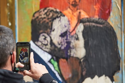 Una persona fotografía con su teléfono el grafiti "Lo que el beso se llevó", una obra del artista urbano TvBoy en la que aparecen pintados Santiago Abascal, Isabel Díaz Ayuso y Pablo Iglesias.