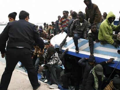 Un policía libio ayuda a desembarcar a unos inmigrantes rescatados tras llegar a Trípoli el domingo.