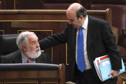 El ministro de Agricultura, Miguel Arias Cañete, 'condenado' por Pajín, charla, bolígrafo en boca, con el diputado socialista Gaspar Zarrías.