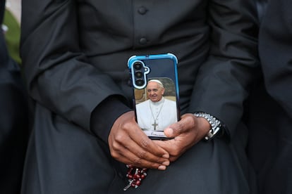Una persona sostiene un teléfono con la imagen del papa Francisco.