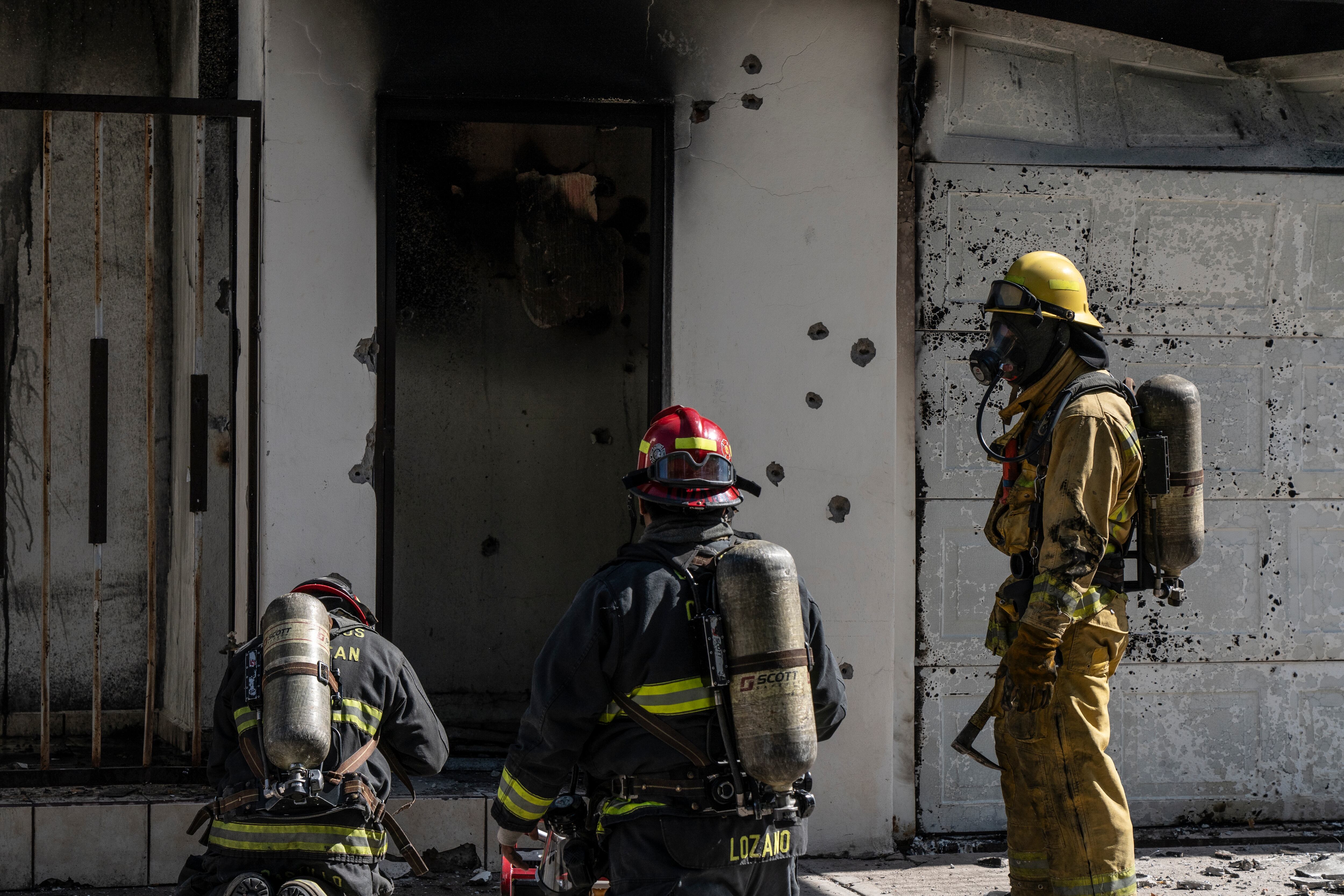 Bomberos apagan el fuego de una casa que fue atacada a balazos y quemada en Culiacán el 25 de noviembre.