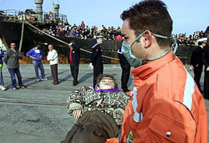 Un policía italiano lleva en brazos a un niño rescatado del mercante <b></b><i>Mónica</i> tras llegar a Catania.