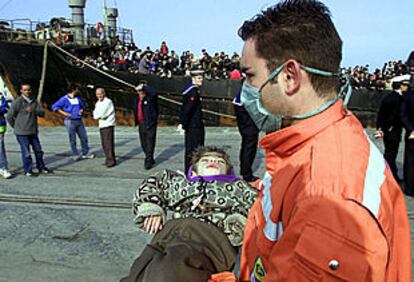 Un policía italiano lleva en brazos a un niño rescatado del mercante <b></b><i>Mónica</i> tras llegar a Catania.