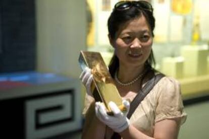 Una visitante posa para una foto con un lingote de oro de 12,5 kilos mientras visita el museo minero del oro de Zhaoyuan Luoshan en la zona rural de Zhaoyuan, en la provinca china de Shandong (China). EFE/Archivo