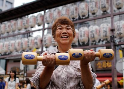 Una mujer se ejercita con pesas de madera durante el evento "Respeta a la gente mayor" en un templo de Tokio (Japón).