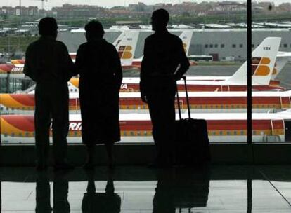 Pasajeros en el aeropuerto de Madrid-Barajas observan aviones de Iberia.