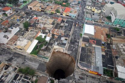 Imagen aérea de un gran socavón en Ciudad de Guatemala tras el paso de la tormenta tropical Agatha. Las autoridades guatemaltecas calculan que el agujero mide 20 metros de  diametro y unos 30 metros de profundidad. Vecinos del barrio ya habían denunciado ciertos ruidos procedentes del subsuelo en los días previos a la tormenta y ya se ha abierto una investigación para determinar el origen del gran socavón.  <a href="http://www.elpais.com/fotogaleria/tormenta/tropical/Agatha/arrasa/America/Central/elpgal/20100531elpepuint_2/Zes/2" target="_blank">Más fotografías de los estragos causados por Agatha</a> .