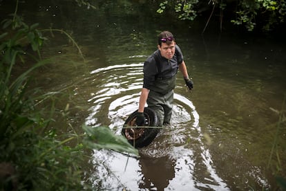 Rubén Rodríguez saca un neumático del fondo del río Lagares (Pontevedra).