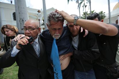 El diputado opositor Américo De Grazia es atendido por guardaespaldas tras ser atacado por partidarios del Gobierno de Nicolás Maduro.