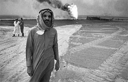 Un hombre frente a un pozo petrolífero ardiendo en Kuwait, durante el conflicto con Irak en 1991.